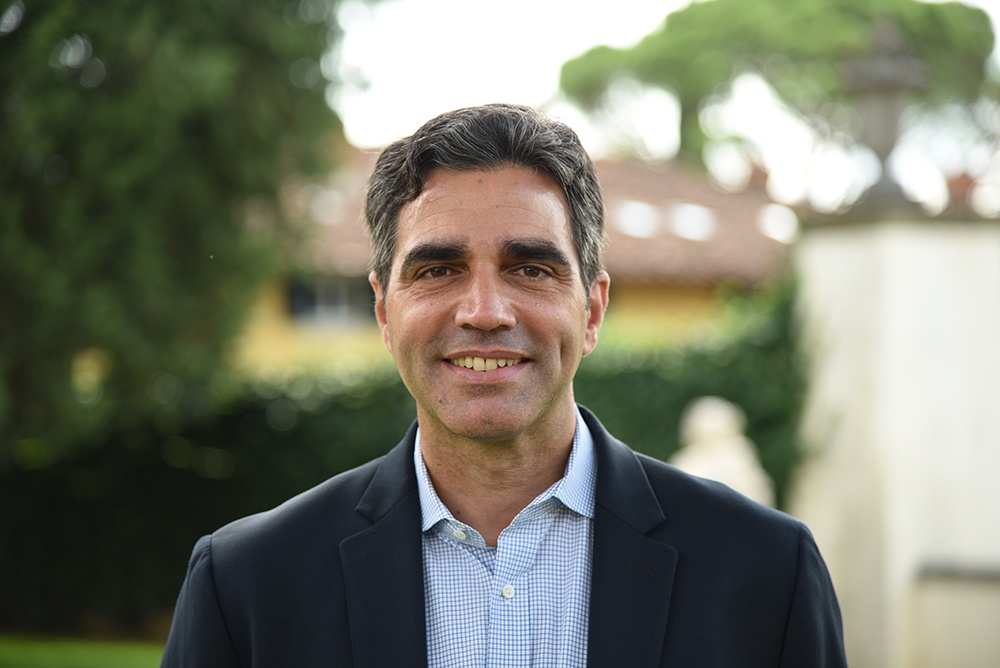 Dr. Joseph Luzzi wearing a shirt and jacket, smiling.